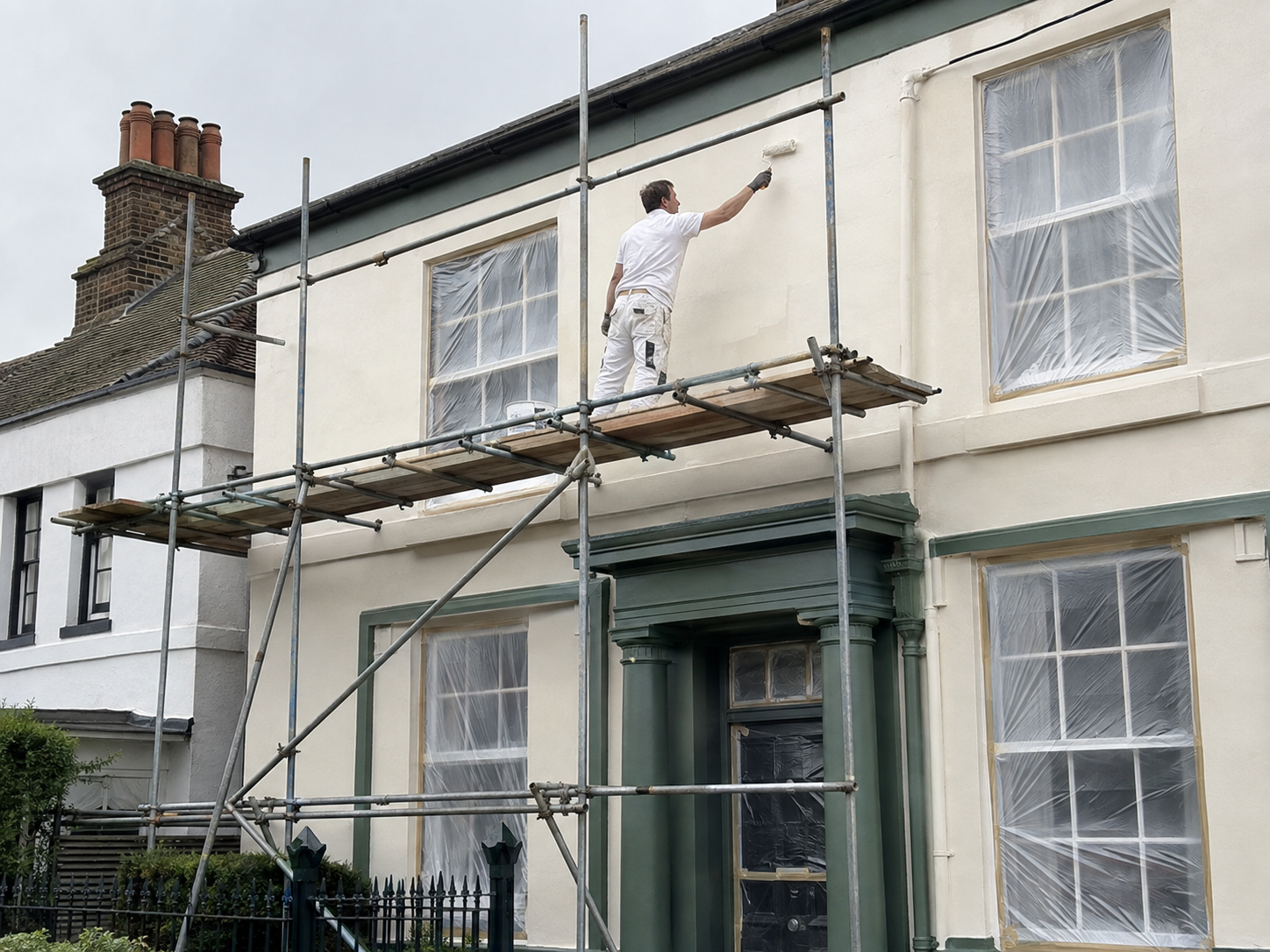 Decorator painting the exterior of a period house using scaffold in Chichester
